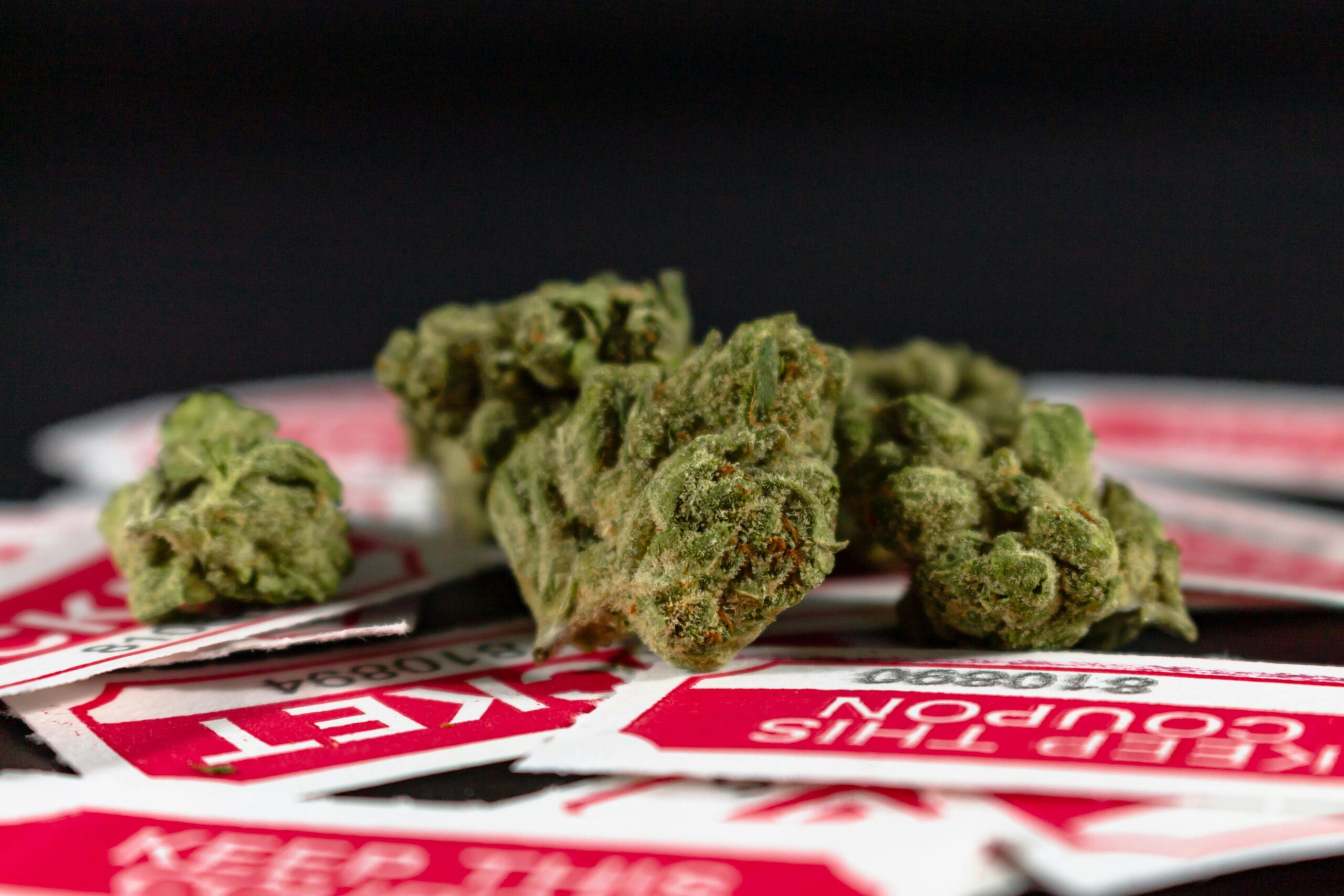High-quality image of cannabis buds on red labels against a dark background.